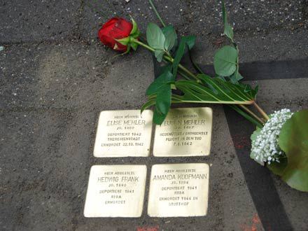 Das Foto zeigt die goldenen Steine mit den Namen Elise Mehler, Eugen Mehler, Hedwig Frank und Amanda Koopmann daneben liegt eine rote Rose